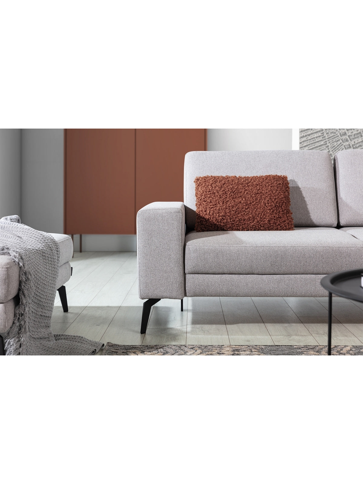 Nowoczesny narożnik z funkcją spania Elentio Mini w jasnoszarym kolorze z metalowymi czarnymi nogami, detal boku i poduszki